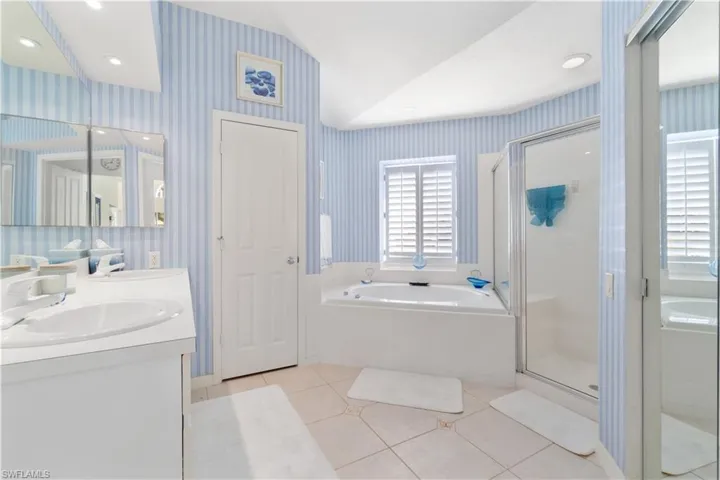 Bathroom featuring plus walk in shower, vanity, tile patterned floors, and lofted ceiling