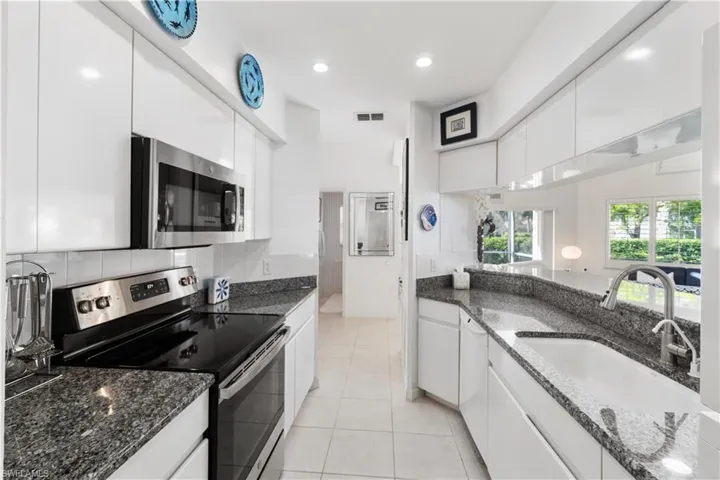 Kitchen featuring stainless steel appliances, white cabinetry, and sink