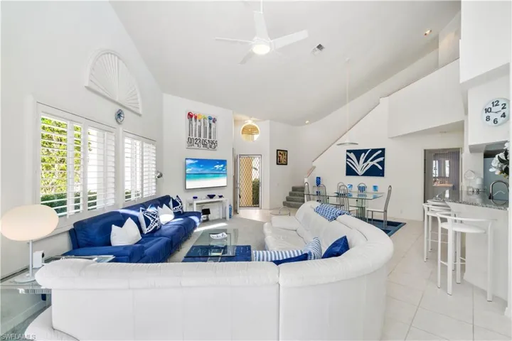 Tiled living room featuring ceiling fan and a towering ceiling