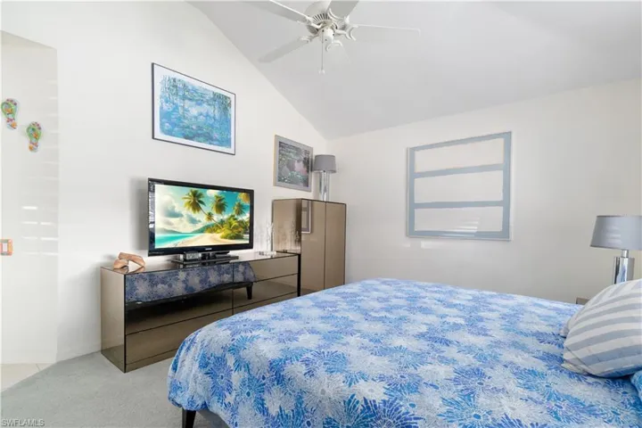 Carpeted bedroom featuring ceiling fan and lofted ceiling