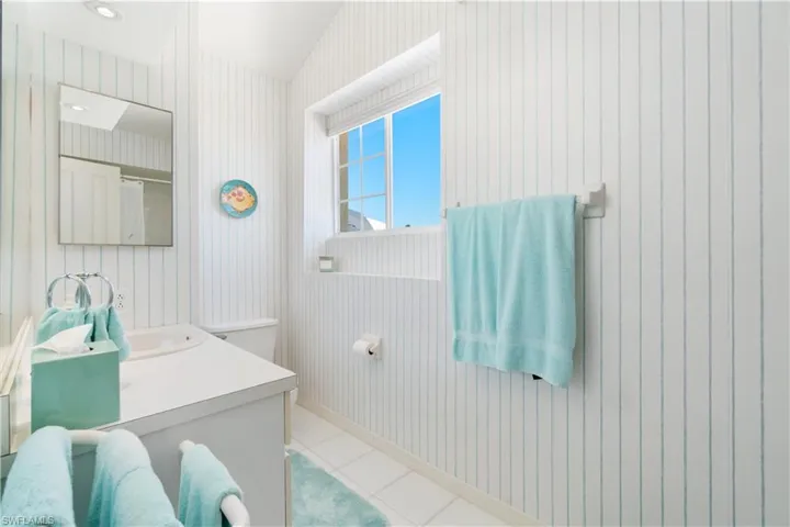 Bathroom featuring tile patterned flooring, vanity, and vaulted ceiling
