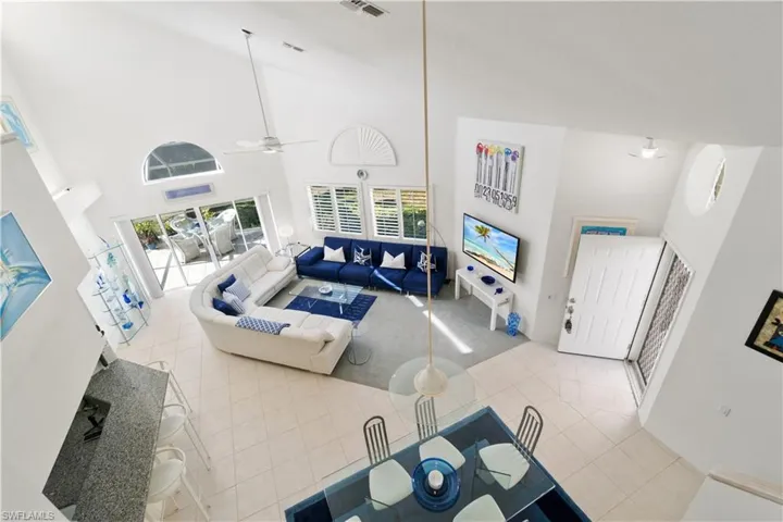 Living room featuring tile patterned flooring, high vaulted ceiling, and ceiling fan