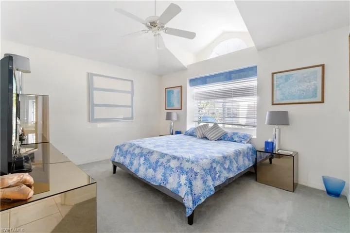 Bedroom featuring ceiling fan, light carpet, and vaulted ceiling