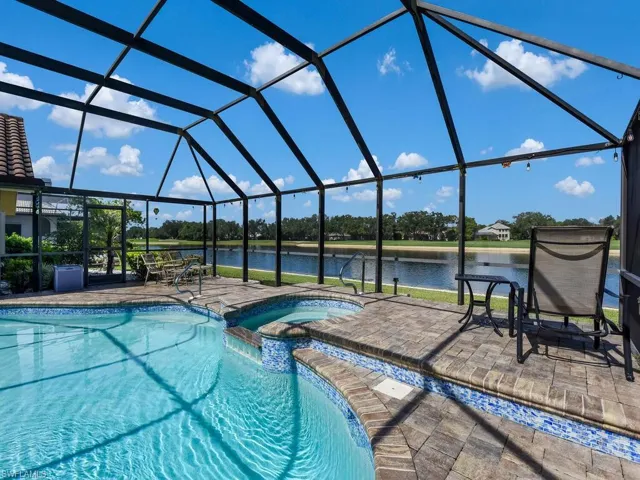 View of pool with a water view, a pool with connected hot tub, a patio, and a lanai