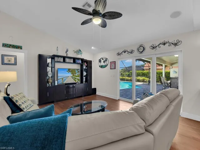 Living room with vaulted ceiling, wood finished floors, a ceiling fan, a sunroom, and recessed lighting