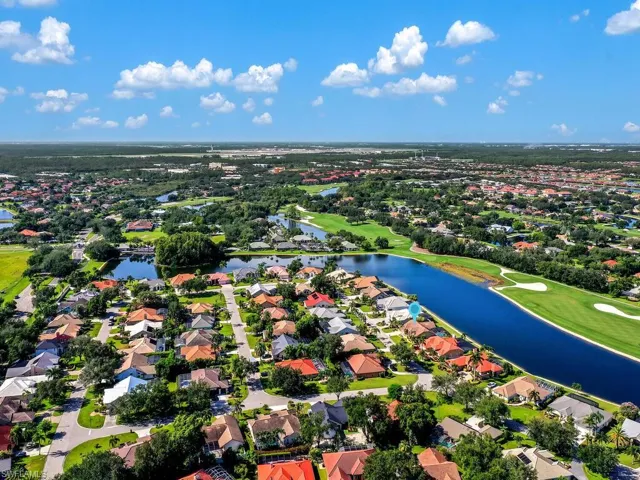 Aerial perspective of suburban area featuring a golf course and a nearby body of water