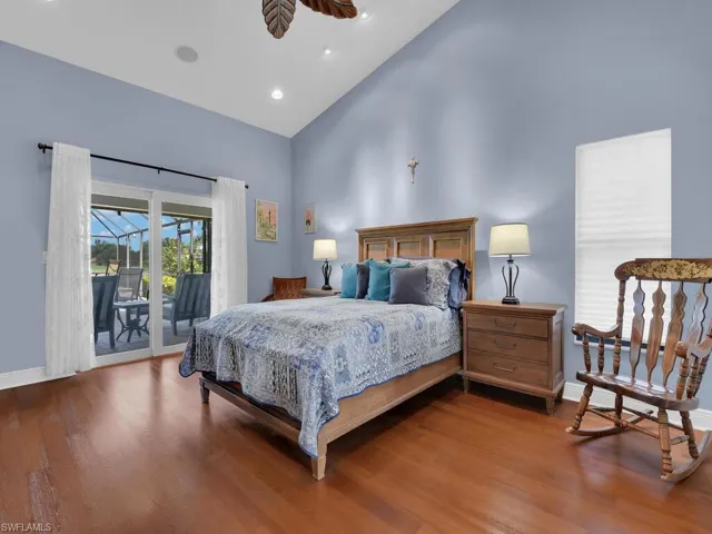 Bedroom with high vaulted ceiling, access to exterior, wood finished floors, and recessed lighting