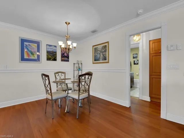 Dining space with a chandelier, ornamental molding, and wood finished floors