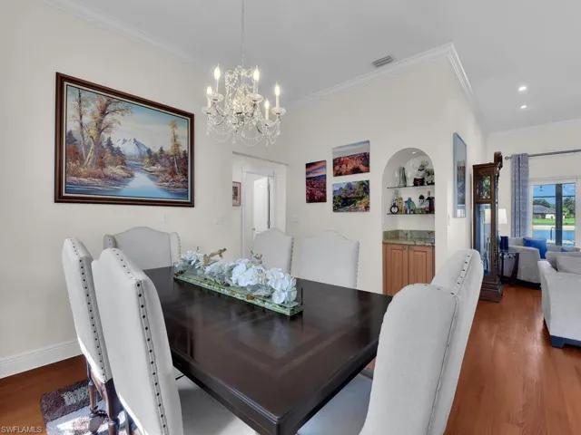 Dining room with crown molding, wood finished floors, built in features, and a chandelier