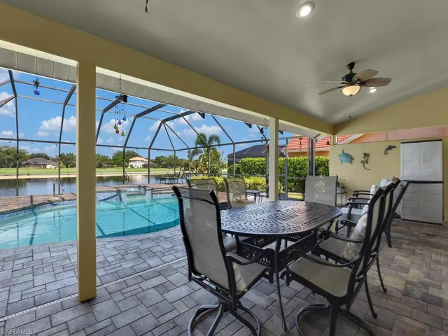 View of patio / terrace featuring a water view, ceiling fan, glass enclosure, and a pool with connected hot tub