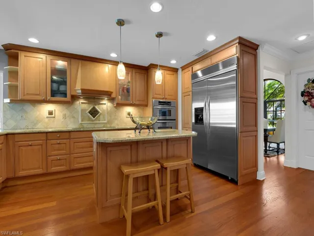 Kitchen featuring appliances with stainless steel finishes, backsplash, ornamental molding, wood finished floors, and recessed lighting