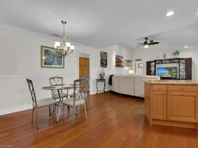 Dining area with dark wood-style flooring, a ceiling fan, and vaulted ceiling