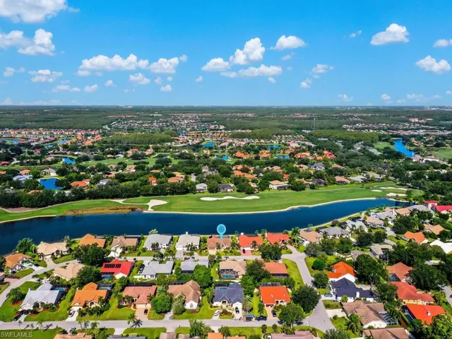 Aerial view of residential area featuring a nearby body of water and a golf club