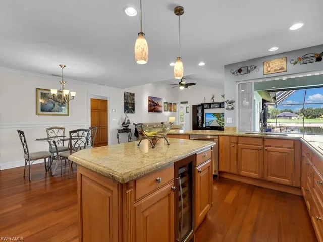Kitchen featuring dark wood-style flooring, light stone countertops, ceiling fan, wine cooler, and brown cabinetry
