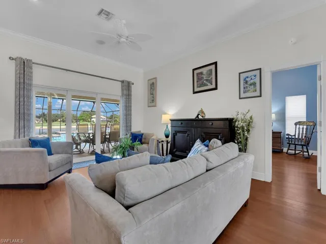 Living area with crown molding, wood finished floors, ceiling fan, and a sunroom