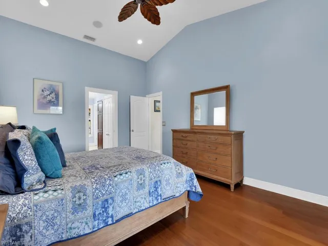 Bedroom featuring wood finished floors, lofted ceiling, recessed lighting, a ceiling fan, and ensuite bath