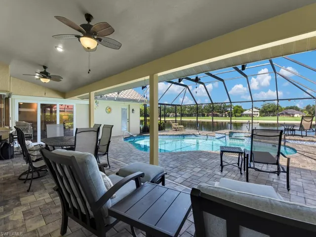 View of pool featuring a patio area, a lanai, a pool with connected hot tub, and a ceiling fan