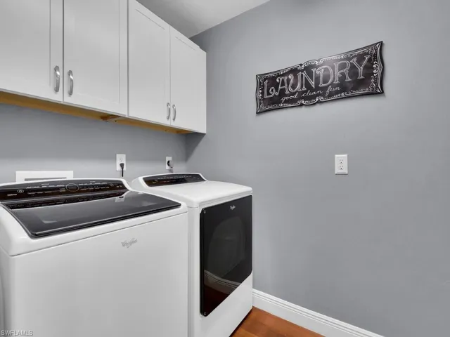 Washroom featuring separate washer and dryer, cabinet space, and wood finished floors