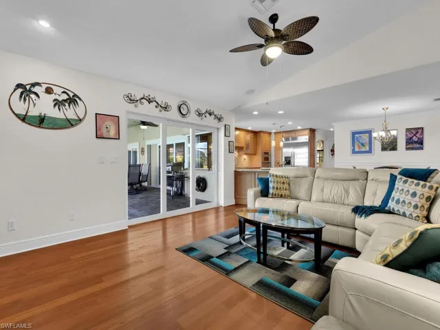 Living room featuring wood finished floors, recessed lighting, ceiling fan, lofted ceiling, and a chandelier