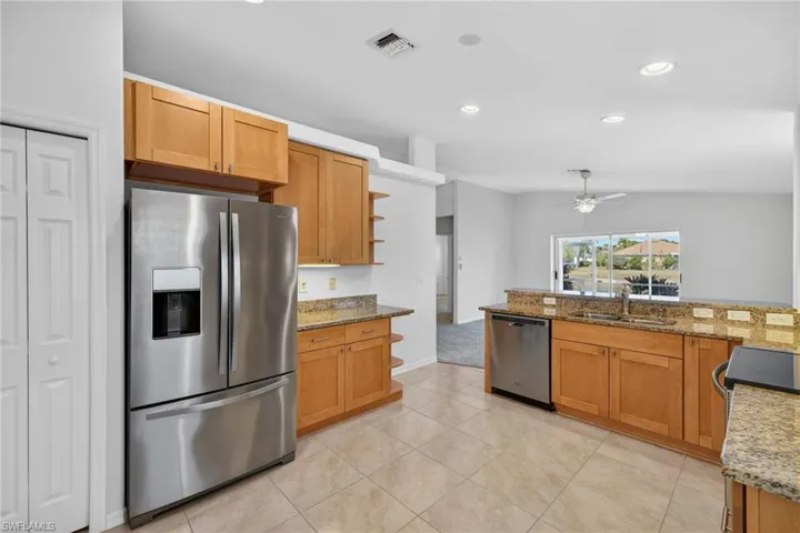 Kitchen with light stone countertops, stainless steel appliances, wood finish cabinetry, recessed lighting, and open shelves