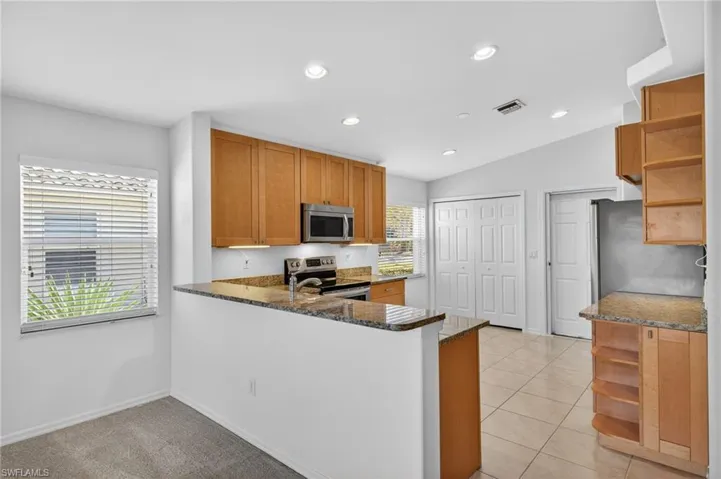 Kitchen with open shelves, dark stone countertops, stainless steel appliances, recessed lighting, and wood finish cabinetry