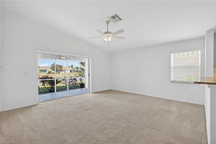 Unfurnished room featuring a ceiling fan, light colored carpet, and vaulted ceiling