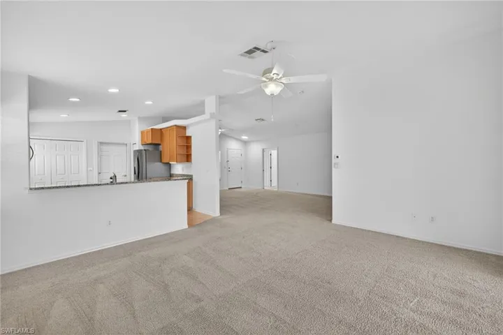 Unfurnished living room with ceiling fan, light colored carpet, lofted ceiling, and recessed lighting