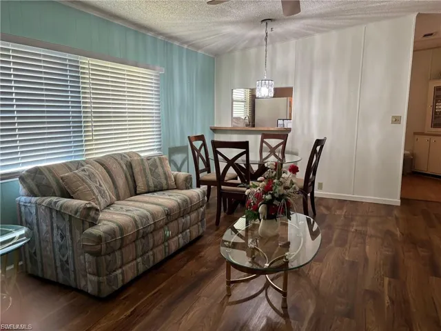Living room with dark wood-style flooring, a textured ceiling, and ceiling fan