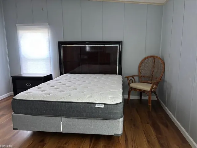 Bedroom with a decorative wall and dark wood-type flooring