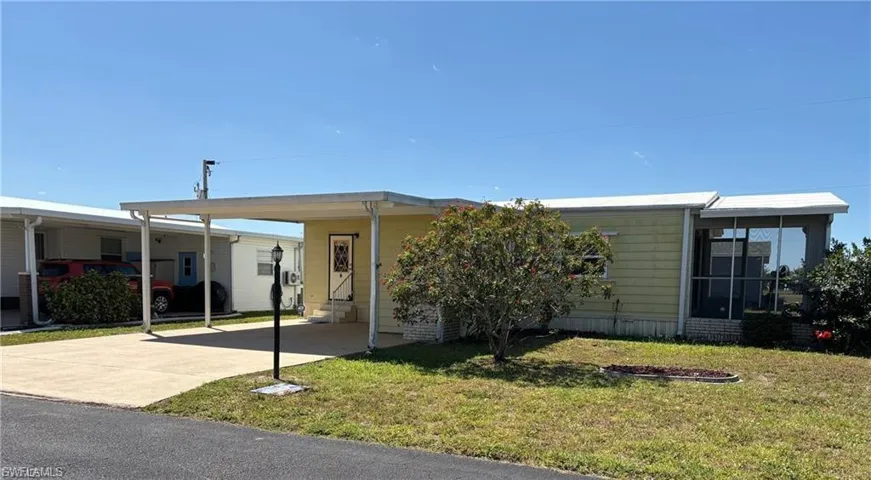 Manufactured / mobile home with a front lawn, a carport, and concrete driveway