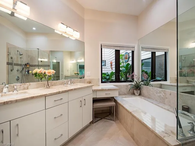Bathroom with a shower stall, double vanity, a garden tub, and atrium views