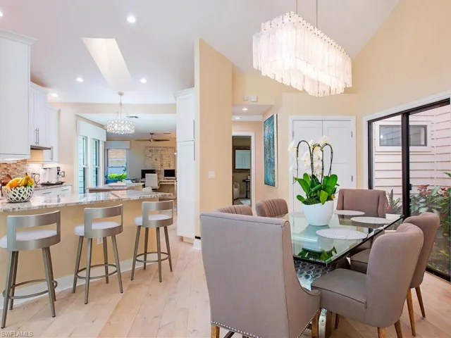 Dining space with suspended lighting, light wood floors and a lofted ceiling