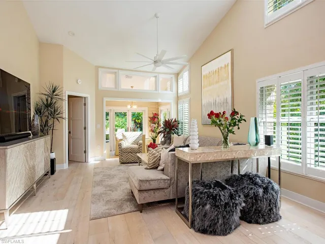 Living area featuring light wood flooring, ceiling fan, and lofted ceiling