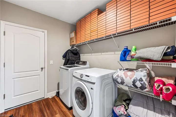 Laundry room with dark hardwood / wood-style flooring and washing machine and dryer