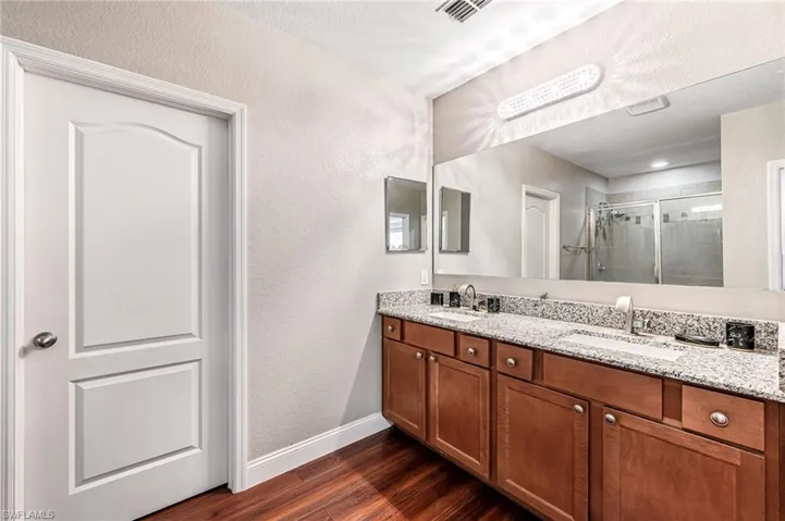 Bathroom with wood-type flooring, double vanity, and walk in shower