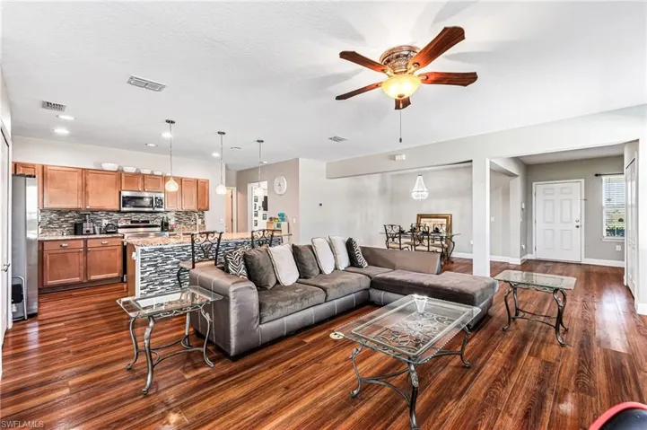 Living room with a textured ceiling, dark hardwood / wood-style floors, and ceiling fan