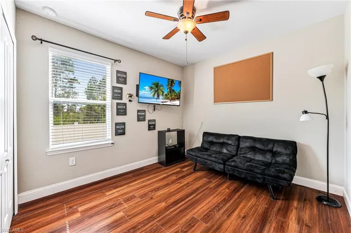 Living area featuring dark wood-type flooring and ceiling fan