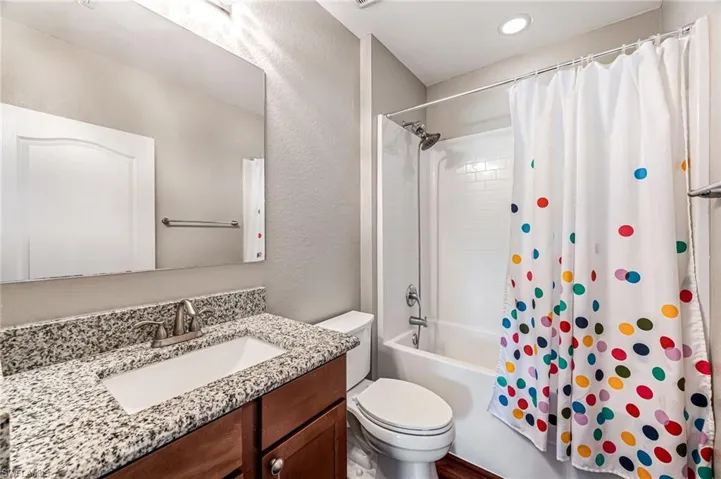 Full bathroom with toilet, vanity, and shower / bath combo