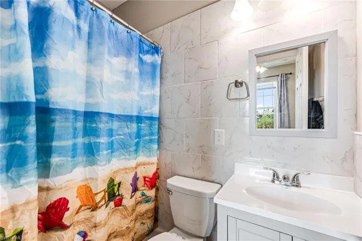 Bathroom with tile walls, toilet, and large vanity