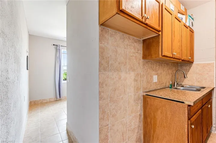 Kitchen with sink, backsplash, and light tile flooring