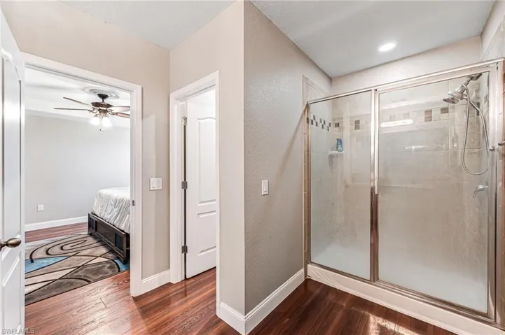 Bathroom with hardwood / wood-style floors, an enclosed shower, and ceiling fan