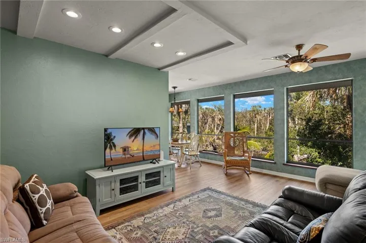Living room featuring light wood-style floors, beamed ceiling, a chandelier, recessed lighting, and a ceiling fan