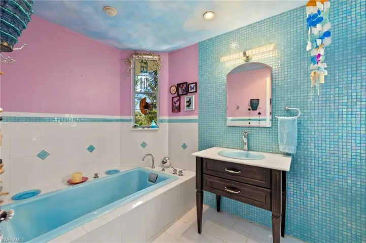 Bathroom featuring tile walls, vanity, a garden tub, and light tile patterned floors