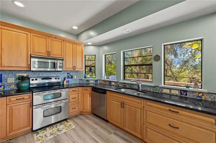 Kitchen with backsplash, stainless steel appliances, dark stone counters, and recessed lighting