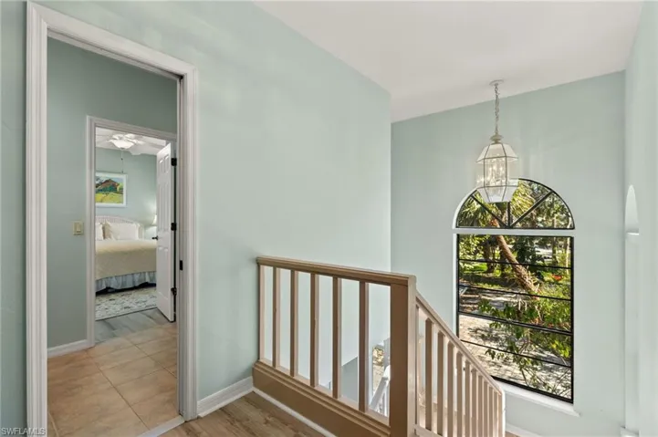 Corridor featuring light wood-style flooring, plenty of natural light, and an upstairs landing