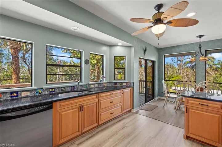 Kitchen with stainless steel dishwasher, dark stone counters, recessed lighting, brown cabinetry, and pendant lighting