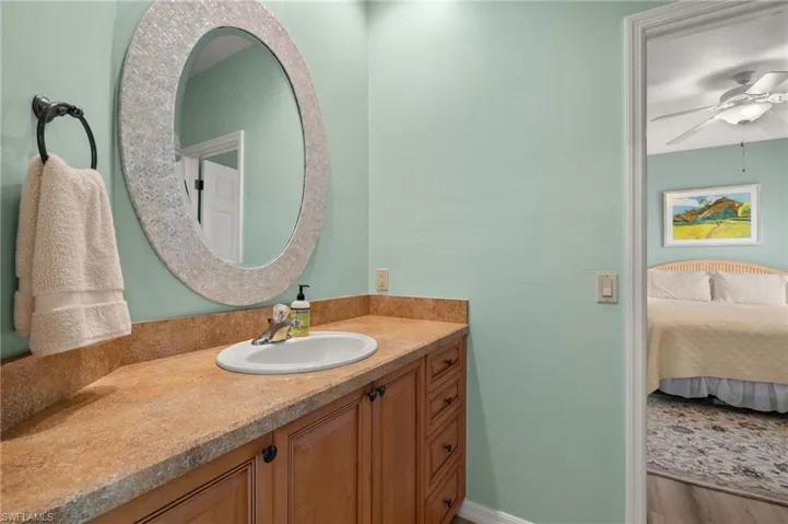 Ensuite bathroom featuring vanity, ceiling fan, and light wood-type flooring