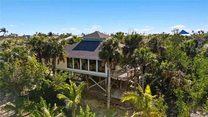 View of property exterior with a deck, roof with shingles, and a sunroom