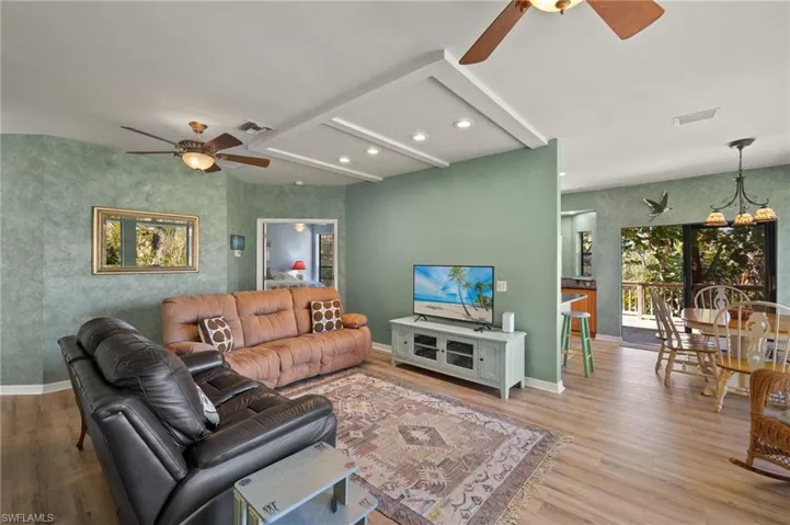 Living area with a ceiling fan, a chandelier, wallpapered walls, wood finished floors, and recessed lighting