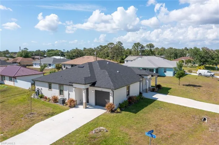 View of front of property featuring a front lawn, roof with shingles, driveway, and a residential view